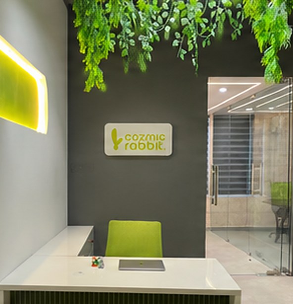 The office reception with a lime chair, hanging plants and the Cozmic Rabbit sign