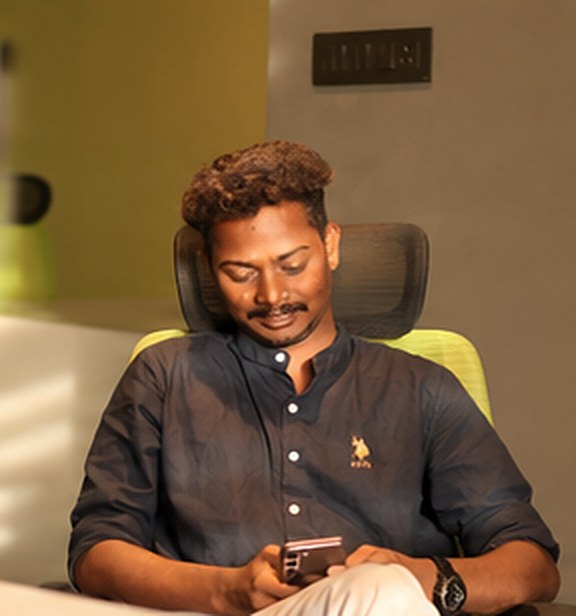 A team member smiling at his phone at his desk